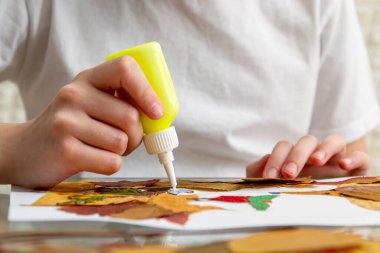 Kız kuru yapraklardan başvuru yapıyor. Çocuklar sonbahar temasına başvururlar. Kirpiler ve elma.