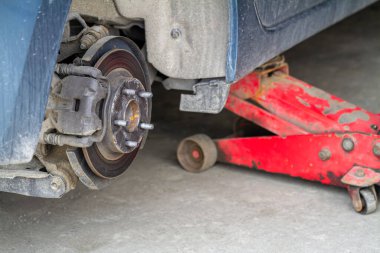 Bir arabanın tekerleklerini değiştirirken, Jack cesedi yüksek pozisyonda tutar. Tekerleksiz araba ve hidrolik kaldırma, lastik değişimi için bekliyor..