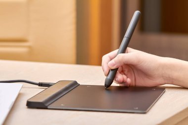 Kız kalemle grafik tabletine resim çiziyor. Yakın çekim, seçici odaklanma