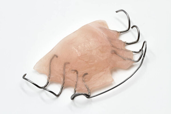 Съемный ортодонтический прибор на светлом фоне. Концепция детской стоматологии, коррекция укуса. Крупный план, большая глубина резкости.