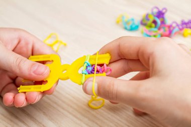 Lastik bantlı dokuma. Dokuma tezgahıyla lastik bantlar örüyorlar. Lastik bileklik takan bir kızın elleri..