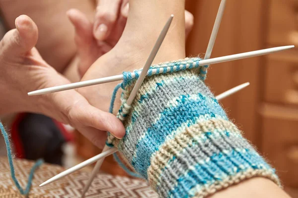 編んでいる間赤ん坊の足の靴下で試みなさい 年配の女性の趣味は編み物です 選択的焦点 — ストック写真