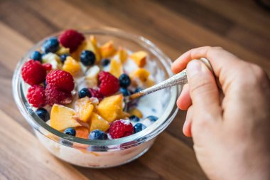Taze meyve ve yoğurtlu kahvaltı kasesi ahududu, yaban mersini ve şeftali ağacından yapılmış tahta bir kasede, sağlıklı beslenme konsepti.