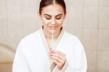 Genç bir kadın tıbbi spa salonunda gerekli yağ burun spreyini alıyor..