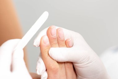 Manikürcünün ellerini tırnak törpüsüyle kadının tırnaklarına manikür yaparken kapatıyoruz..