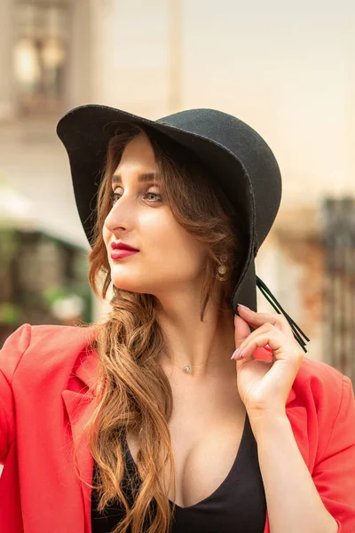 街の通りを離れて見て赤いコートと黒の帽子でファッショナブルな若い女性のサイドビュー — ストック写真