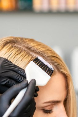 Kuaför elleri. Güzellik salonunda fırçayla kadın saçı boyuyor..