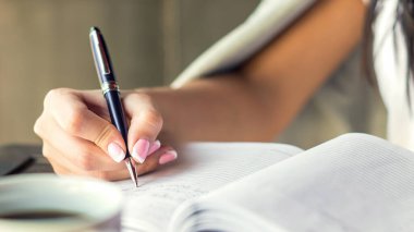 Kafede küçük bir günlük üzerine planlar yazan genç bir kadın. İş konsepti