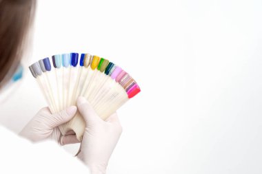 Manikürcü elleri manikür tırnak renk paletini beyaz arkaplanda fotokopi alanı ile tutuyor.