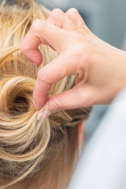 Sarışın bir kadının uzun saçı için kuaför saç stili yaparken yakın plan..