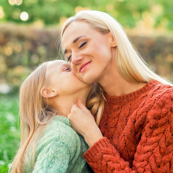 Cute Córka Całuje Swoją Młodą Matkę Siedząc Parku — Zdjęcie stockowe