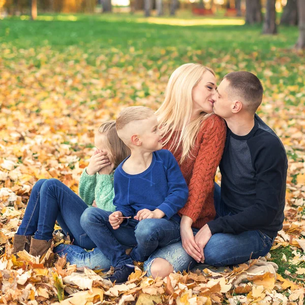 Portret Młodej Rodziny Siedzącej Jesiennych Liściach Rodzice Całują Się Siedzą — Zdjęcie stockowe