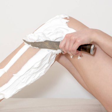 Beyaz arka planda bıçakla tıraş olurken köpüklü güzel kadın bacakları.