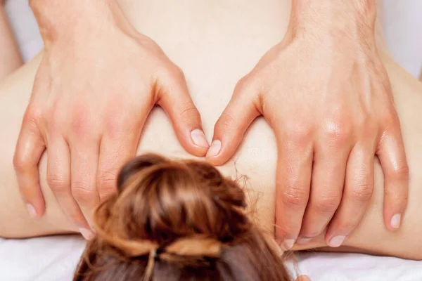 Shoulder massage of woman by hands of massage therapist, close up.