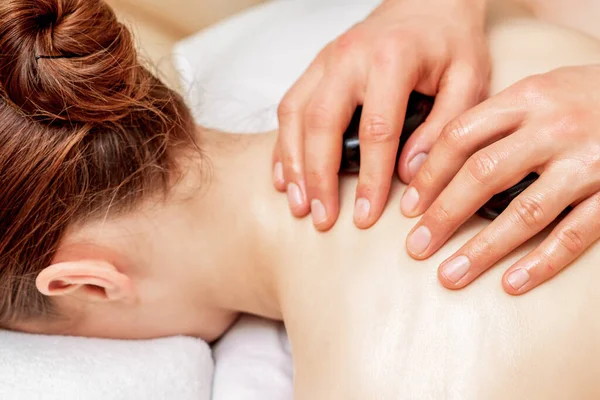 Masaj terapisti sırtında taş taşırken sırtında taş olan genç bir kadın..