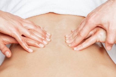 İki erkek terapistin dört eliyle sırt masajı yaptıran adam..