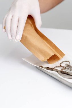 Kadın manikür ustası el, el işi zarftan manikür aletleri çıkarıyor.