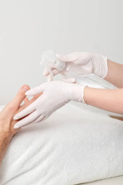 Nurse hand sanitizing hands of male patient in the hospital. Coronavirus protection concept.