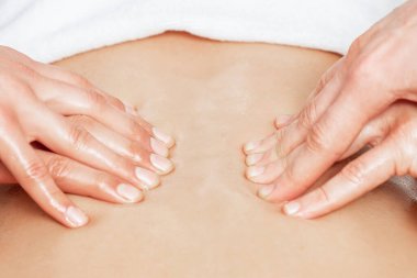 İki erkek terapistin dört eliyle sırt masajı yaptıran adam..