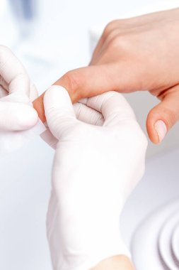 Manikür ustası güzellik salonunda beyaz pamukla oje çıkarıyor.