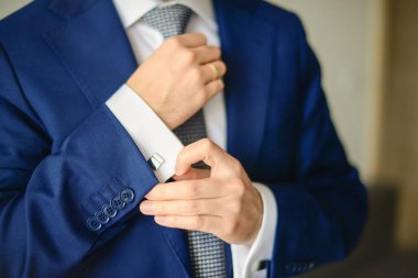 Damat ya da işadamı, mavi takım elbise giyen gömleğin kol düğmesini takın. Seçici odak