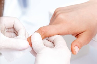 Manikür ustası güzellik salonunda beyaz pamukla oje çıkarıyor.