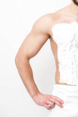 Sakallı beyaz bir adam göğsünü tıraş eder ve beyaz arka planda tıraş köpüğü vardır. Adam gövdesini tıraş ediyor.