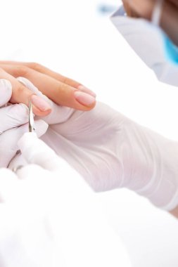 Manikürcünün manikür salonundaki kadın tırnaklarını sökmek için manikür makası kullanmasını kapat.