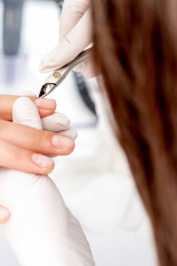 Manikürcünün manikür makasıyla manikür salonundaki kadın tırnaklarının derisini yüzmek için.