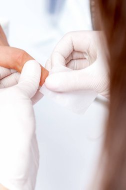 Manikür ustası güzellik salonunda beyaz pamukla oje çıkarıyor.