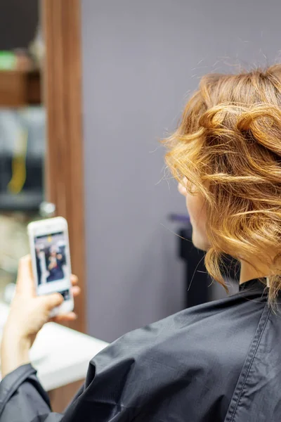 Friseur Frisiert Junge Frau Mit Roten Locken Und Smartphone Der — Stockfoto