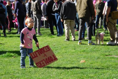 A young boy stands with a sign that says 