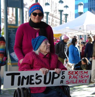 A woman in a wheelchair with a sign that says 