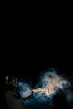 Beyaz keten kostümlü ve renkli dumanlı bir adam. Koyu arkaplan