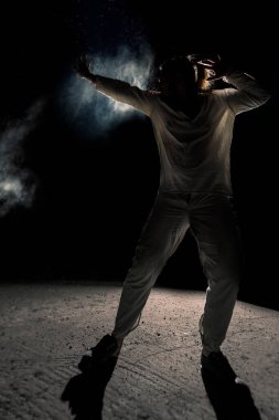 Beyaz keten kostümlü ve renkli dumanlı bir adam. Koyu arkaplan