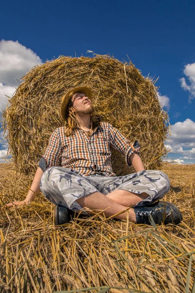 Kovboy şapkalı, buğday ekmekli, sakallı genç bir adam.