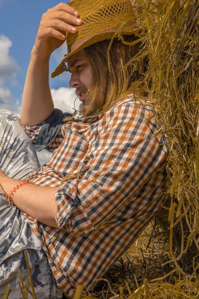 Kovboy şapkalı, buğday ekmekli, sakallı genç bir adam.