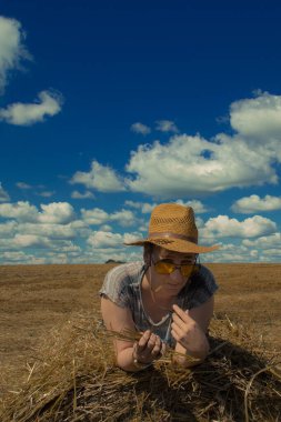 Kovboy şapkalı ve buğday ekmekli sarı güneş gözlüklü bir kadın.