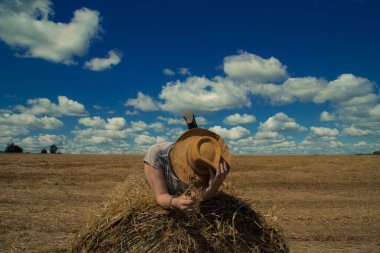 Kovboy şapkalı ve buğday ekmekli sarı güneş gözlüklü bir kadın.