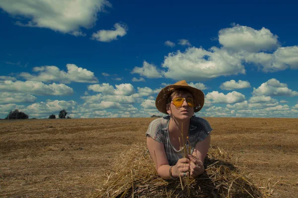 Kovboy şapkalı ve buğday ekmekli sarı güneş gözlüklü bir kadın.