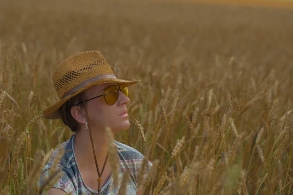 Kovboy şapkalı ve buğday tarlasında sarı güneş gözlüklü bir kadın.