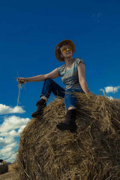 Kovboy şapkalı ve buğday ekmekli sarı güneş gözlüklü bir kadın.