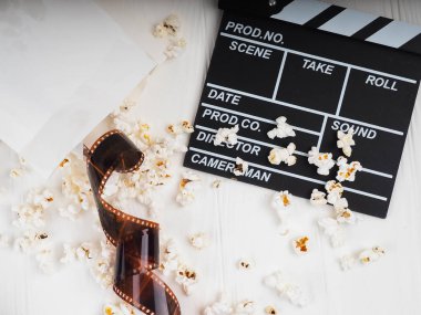 the film in the spiral, near the popcorn, Clapperboard copy space for text, fashion highlights in the photo, concept, film industry, film, abstract composition of movie, on a white background. clipart