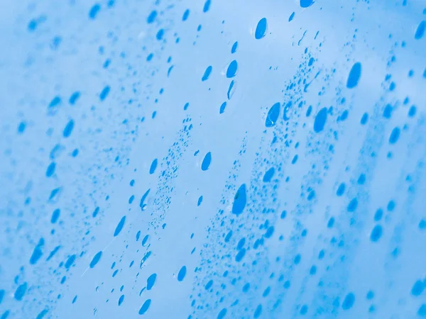 Drops of rain background texture on blue glass background, drops on glass after rain.
