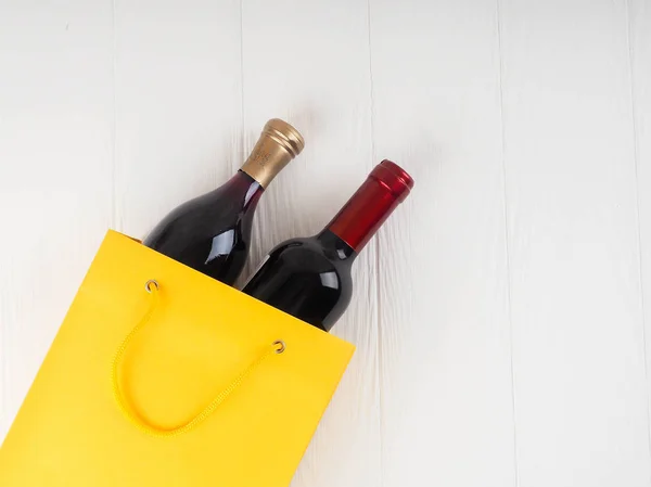 bottle of wine and flowers in the package on wooden background, space for text.