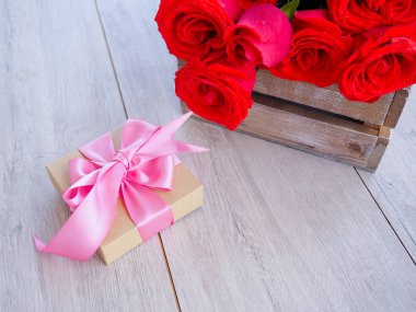 Kurdele ve yay ve ahşap kırmızı güller demet ile hediye kutusu Valentine arka plan. Kopyalama alanı