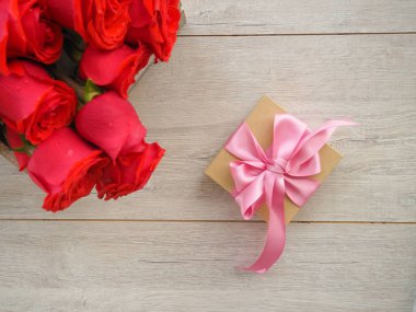 Kurdele ve yay ve ahşap kırmızı güller demet ile hediye kutusu Valentine arka plan. Kopyalama alanı