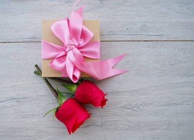 Kurdele ve yay ve ahşap kırmızı güller demet ile hediye kutusu Valentine arka plan. Kopyalama alanı