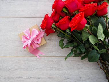 Kurdele ve yay ve ahşap kırmızı güller demet ile hediye kutusu Valentine arka plan. Kopyalama alanı