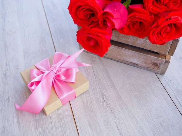 Kurdele ve yay ve ahşap kırmızı güller demet ile hediye kutusu Valentine arka plan. Kopyalama alanı